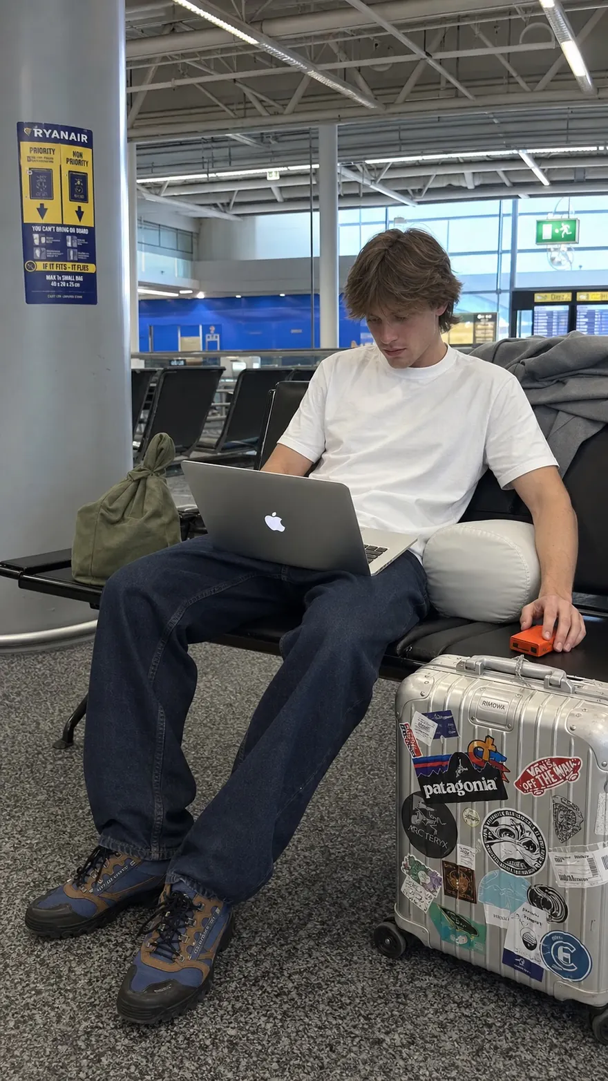 Airport Bench Layover: Working on a laptop at the terminal, Rimowa case beside him