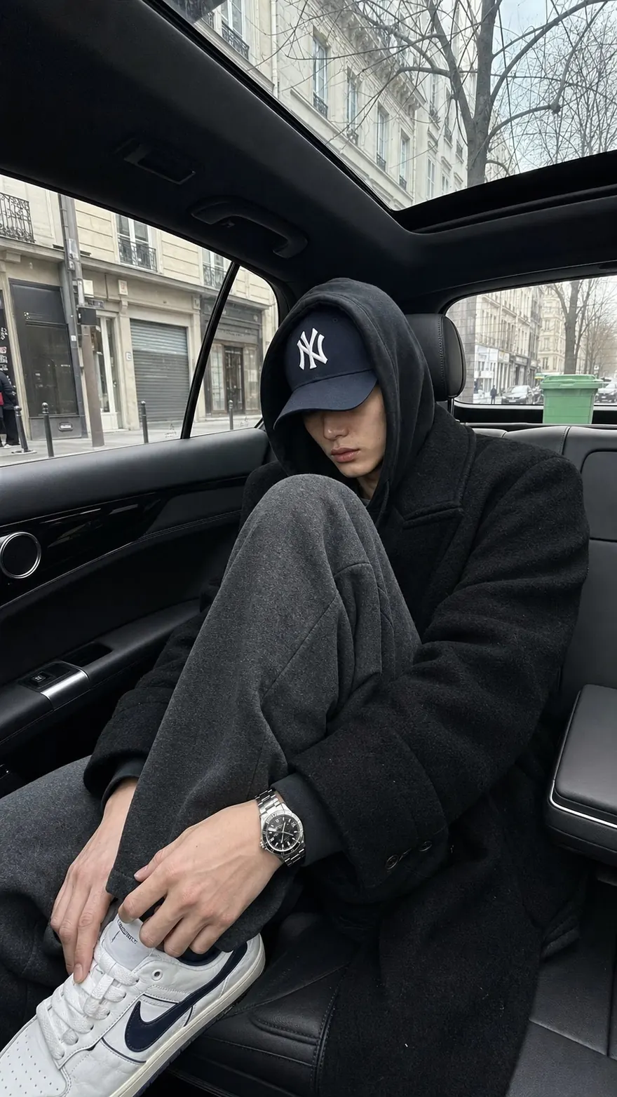 Backseat, Yankees Cap: Curled up in the rear seat, hood up, grey city street outside