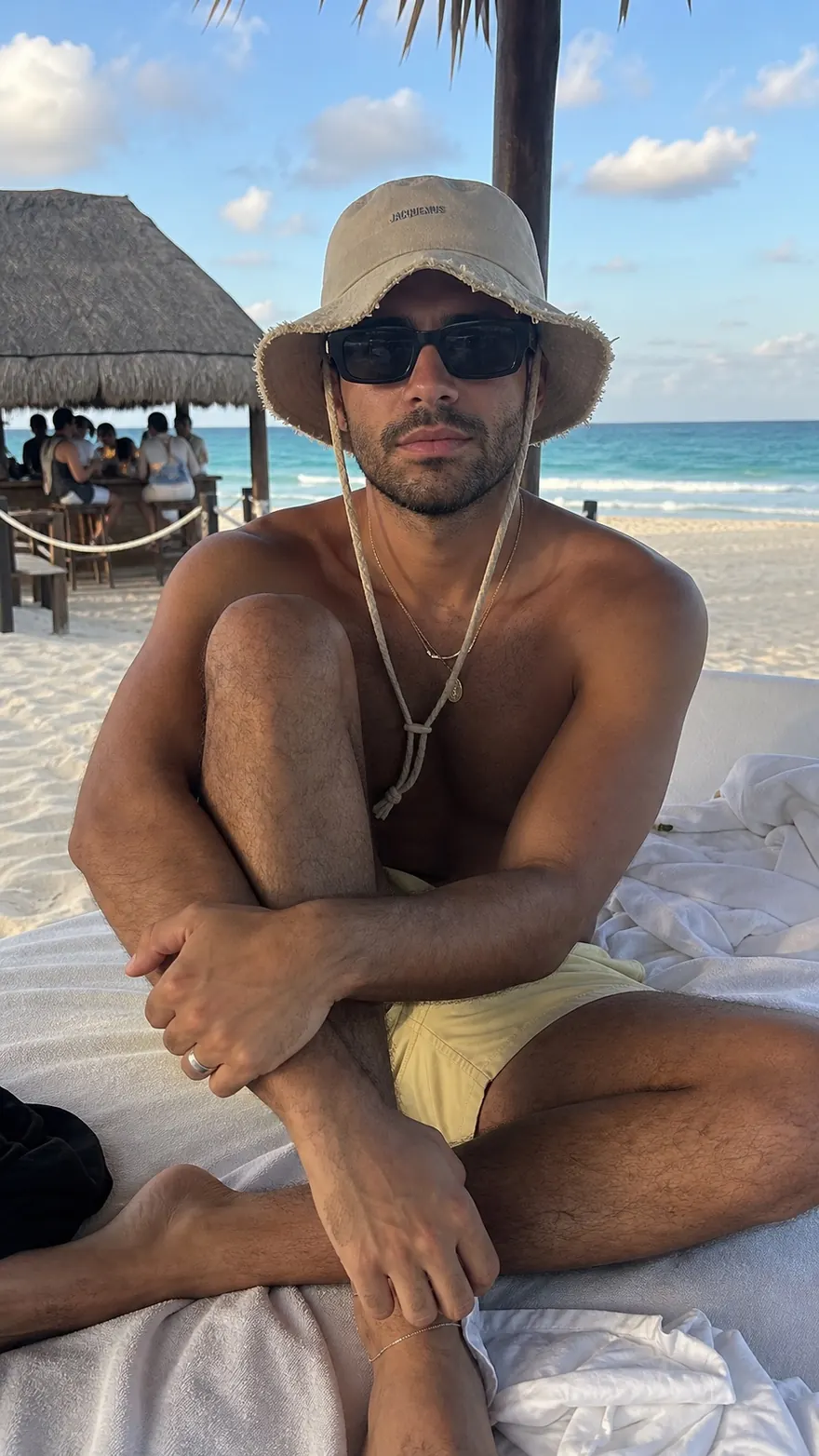 Beach Daybed: Seated on a white daybed in a frayed bucket hat