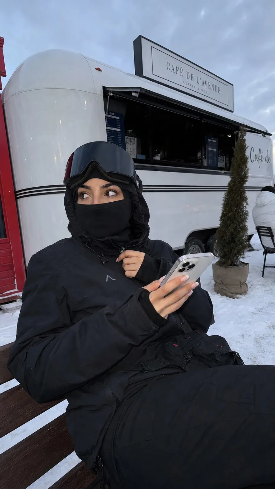 Snow Cafe Break: Bundled up on a bench outside a snowy coffee trailer