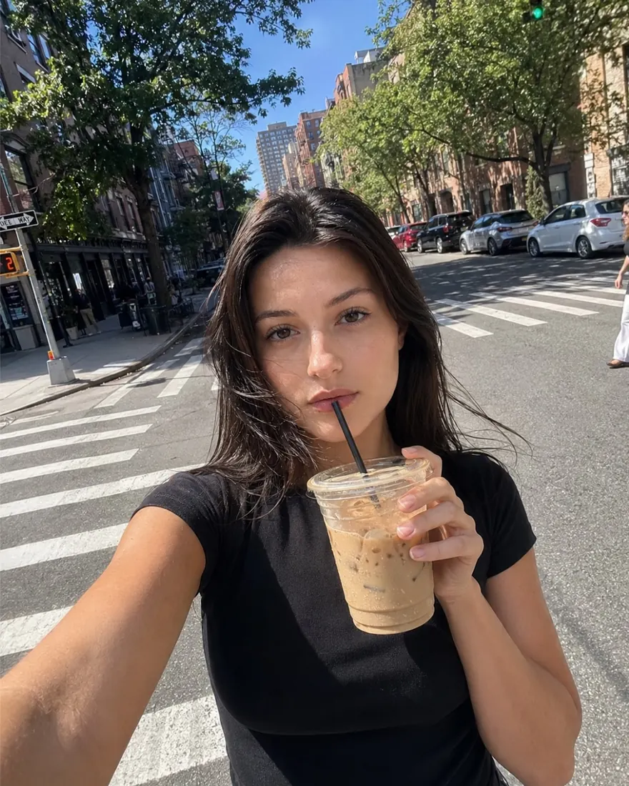 NYC Street Selfie: Arm's-length selfie crossing a city street, iced coffee in hand